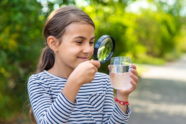 Das Kind untersucht das Wasser mit einer Lupe Selektiver Fokus