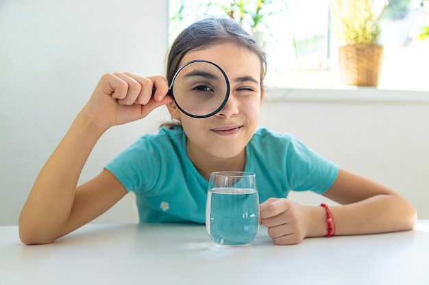 Das Kind untersucht das Wasser unter einer Lupe Selektiver Fokus