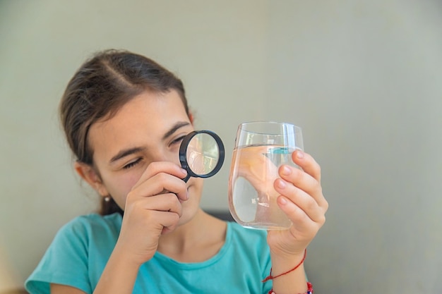 Das Kind untersucht das Wasser unter einer Lupe Selektiver Fokus