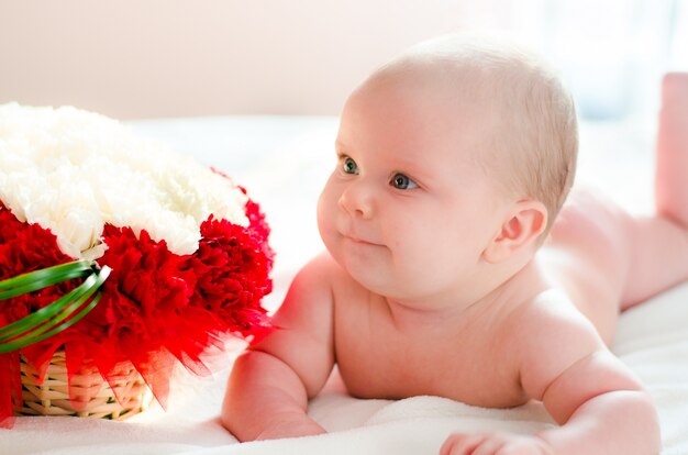 Das kleine Baby liegt in der Nähe der Blumen