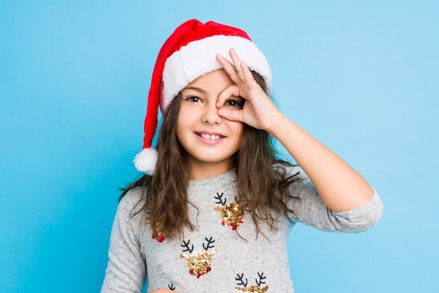 Das kleine Mädchen, das Weihnachtstag feiert, regte das Halten der okaygeste auf Auge auf.