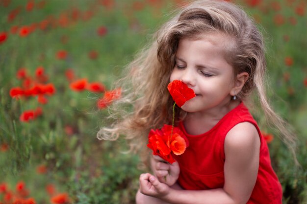 Das kleine Mädchen im roten Kleid, das rote Blume riecht