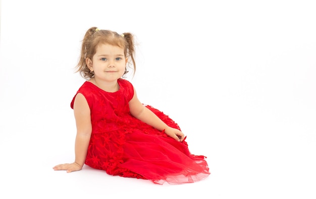 Das kleine Mädchen in leuchtend rotem Kleid auf einem weißen Oberflächenkopierraum
