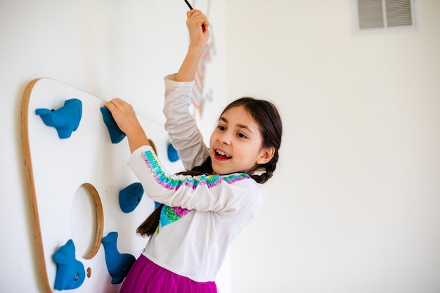 Das kleine Mädchen klettert im Spielzimmer an der Wand