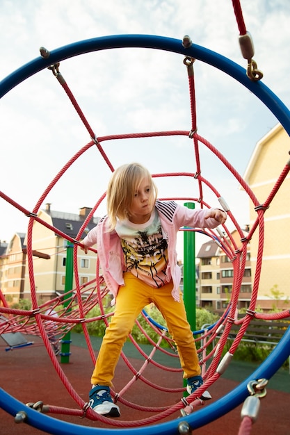 Das kleine Mädchen klettert Seile auf dem Spielplatz