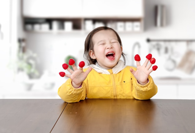 Das kleine Mädchen spielte mit Himbeeren an den Fingern