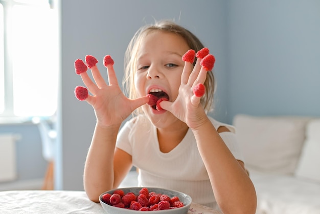 Das kleine Mädchen spielte mit Himbeeren an den Fingern