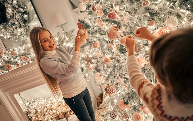 Das kleine Mädchen und der Junge schmücken den Weihnachtsbaum