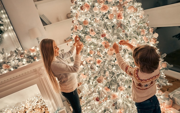 Das kleine Mädchen und der Junge schmücken den Weihnachtsbaum