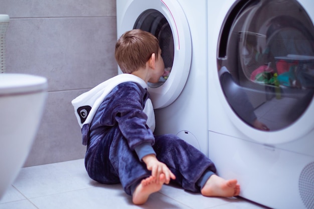Das Kleinkind schaut beim Waschen in die Waschmaschine
