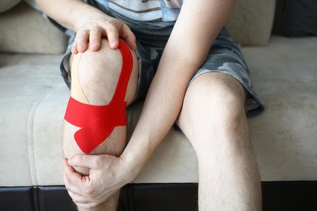 Das Knie eines kranken Mannes wird mit Kinesio-Tape versiegelt