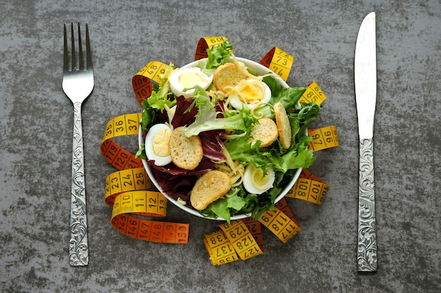 Das Konzept der diätetischen Ernährung. Gesunder Salat mit Wachteleiern und grünen Blättern. Maßband. Das Konzept des Gewichtsverlusts durch Ernährung.