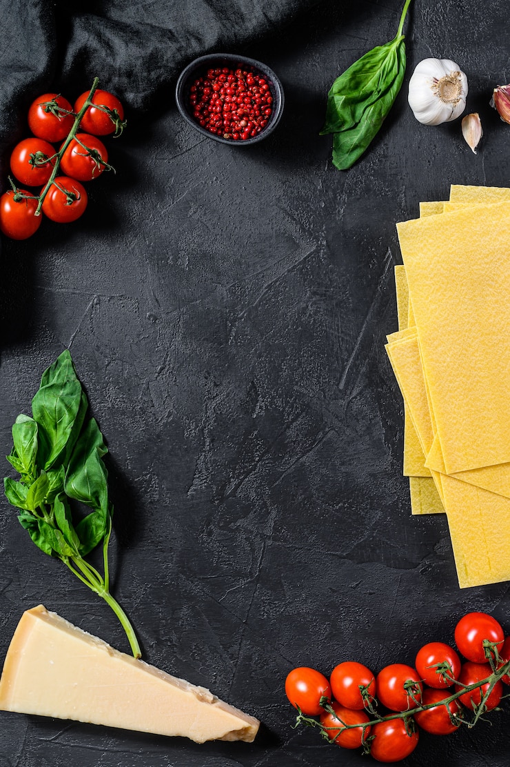 Foto das konzept der lasagne kochen. zutaten, lasagneblätter, basilikum, kirschtomaten, parmesan, knoblauch, pfeffer. ansicht von oben. copyspace hintergrund
