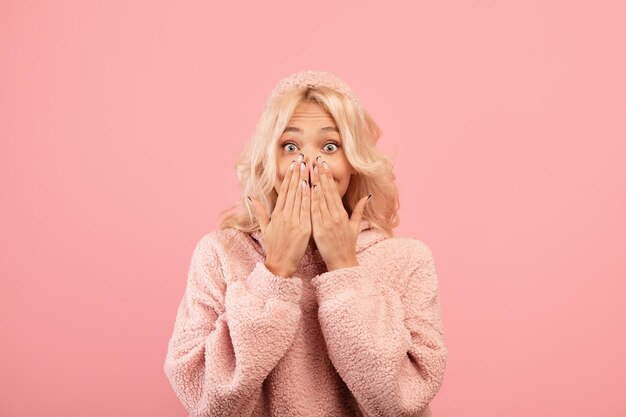 Das Konzept der menschlichen Emotionen schockierte die Dame, die ihren Mund mit den Händen bedeckte und die Kamera rosa ansah