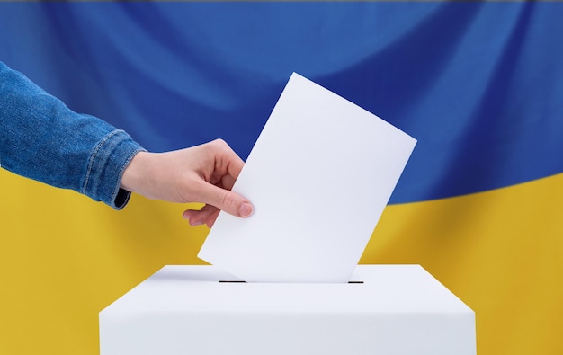 Foto das konzept der wahlen eine menschliche hand wirft einen stimmzettel in die wahlurne wahlen in der ukraine