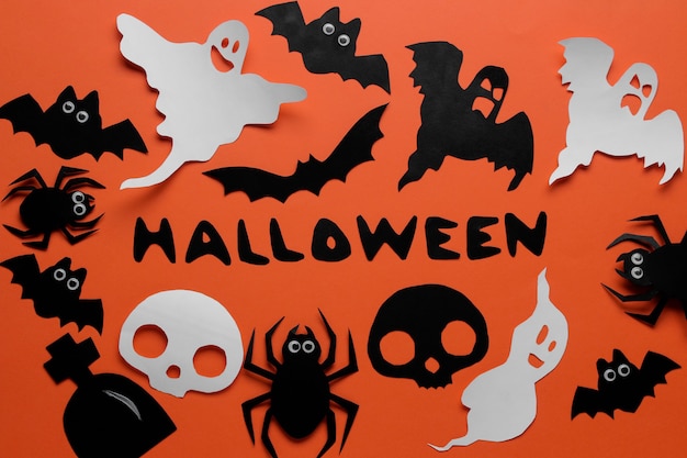 Das Konzept des Feiertags von Halloween. Fledermäuse der Besetzung und Spinnen auf orangem Hintergrund. Ansicht von oben