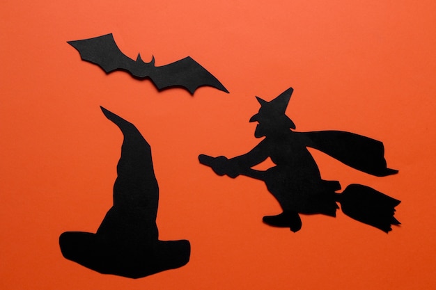 Das Konzept des Feiertags von Halloween. Hexe und Schläger auf orangem Hintergrund. Ansicht von oben