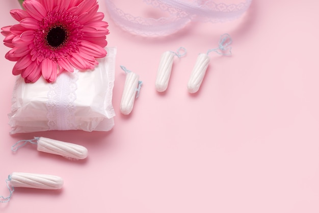 Das Konzept des Menstruationszyklus bei Frauen. Tampons und Pads neben einer Blume.