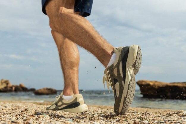 Das Konzept des Sports, das am Strand läuft, Beine aus nächster Nähe