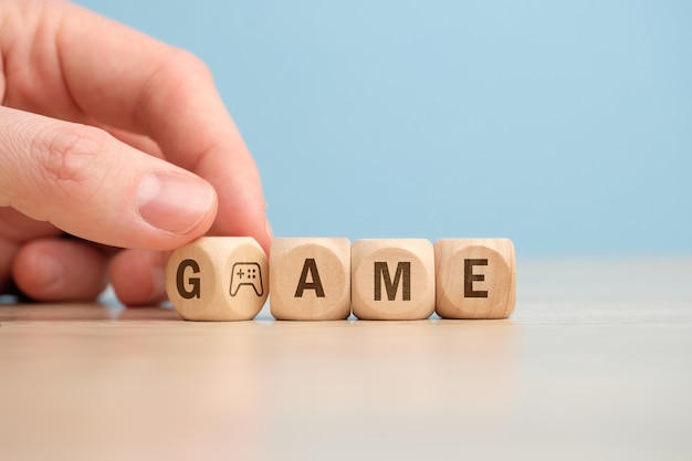 Das Konzept einer Spielauswahl mit einem Joystick-Symbol auf Holzwürfeln wird von Hand umgedreht.