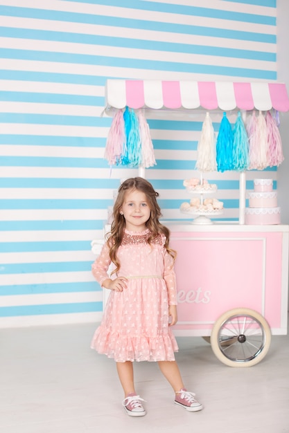 Das Konzept von Geburtstag und Glück - ein glückliches kleines Mädchen steht in einem schönen Kleid