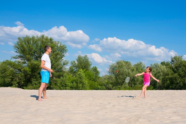 Das Konzept von Sport und aktiven Spielen im Sommer Vater und Tochter spielen Badminton am Strand