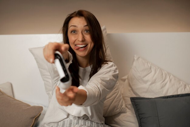 Das lächelnde Mädchen im Bett spielt auf der Konsole und hält den Joystick in den Händen