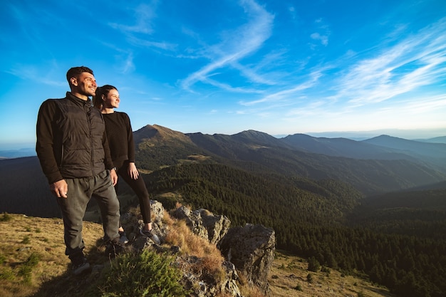 Das lächelnde Paar, das auf dem schönen Berglandschaftshintergrund steht