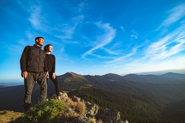 Das lächelnde Paar, das auf dem schönen Berglandschaftshintergrund steht