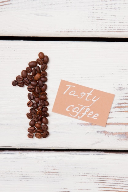 Das leckerste Kaffeekonzept. Kaffeebohnen in Form von Nummer eins und Papaer mit leckerem Kaffeesatz auf weißem Holz.