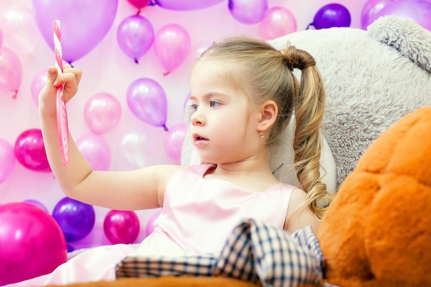 Das lustige kleine Mädchen schaut aufmerksam auf den Lolli