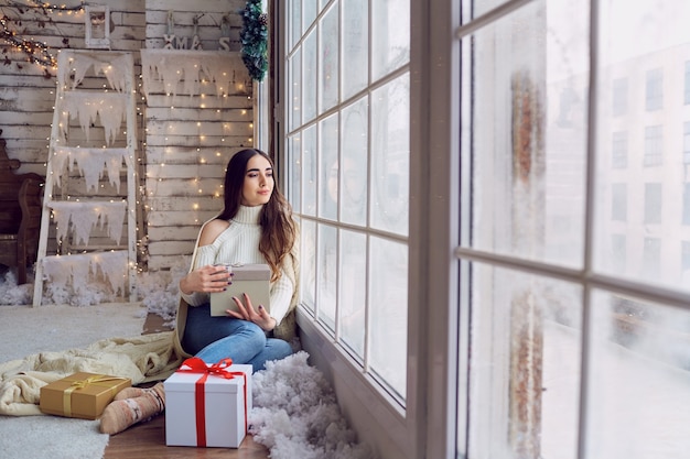 Das Mädchen am Fenster mit Geschenken im Winter