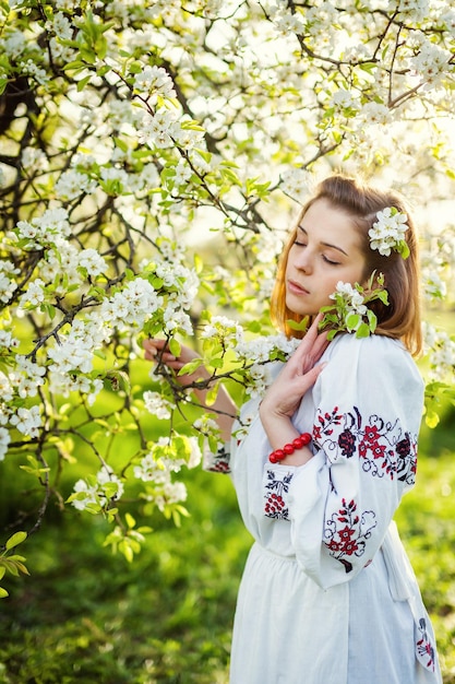 Das Mädchen am Frühlingsmorgen in einem wunderschönen Blumengarten, der einen Blumenstrauß in den Händen hält