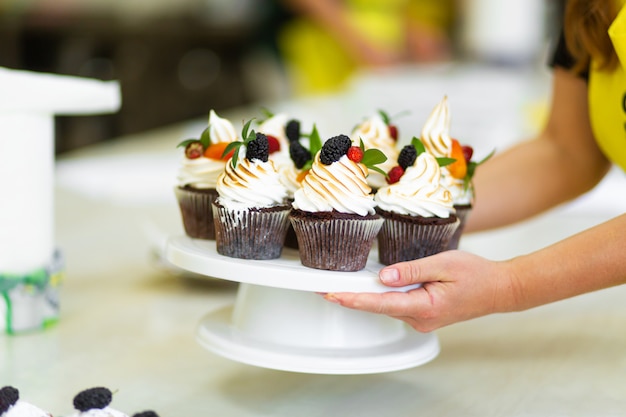 Das Mädchen behandelt ihre Freunde mit den süßen Muffins, die sie gebacken hat. Süßes Gebäck, Rezepte, Kochen