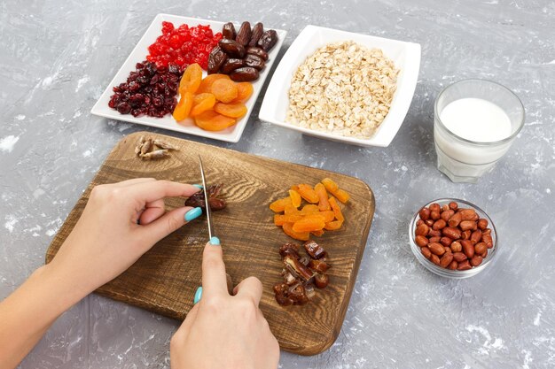 Das Mädchen bereitet ihr Frühstück zu Das Mädchen schneidet ihre Dattelfrüchte in Haferbrei auf einem Schneidebrett Nützliches und gesundes Frühstück auf grauem Hintergrund Draufsicht