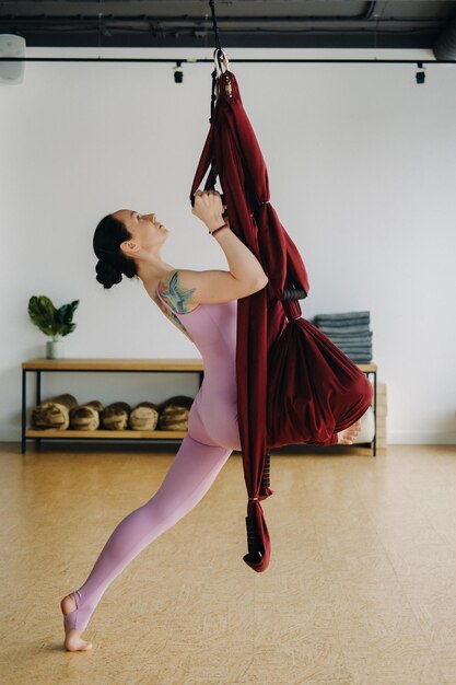 Das Mädchen beschäftigt sich mit Aerial Yoga und macht Dehnübungen auf einer Hängematte im Fitnessstudio