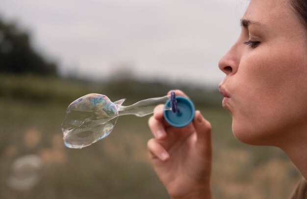 Das Mädchen bläst Seifenblasen Eine junge Frau sitzt in der Natur und bläst Seifenblasen Gesicht im Profil