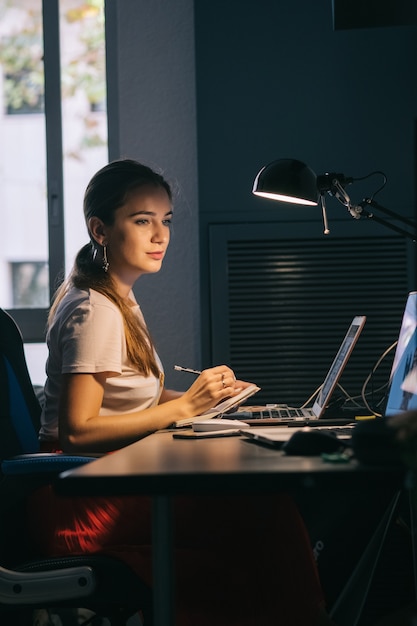 Das Mädchen, das am Computer arbeitet, konzentriert sich auf die Arbeit im Büro, das auf der Suche nach einer neuen Idee konzipiert wurde