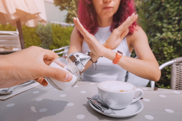 Das Mädchen ernährt sich gesund und weigert sich, ihrem Kaffee Zucker hinzuzufügen. Das Konzept von Krankheiten durch einen Überschuss an schnellen Kohlenhydraten und Diabetes