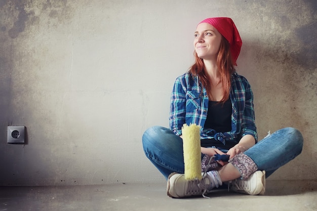 Das Mädchen führt Reparaturen in der Wohnung durch. Umzug in eine neue Wohnung. Der Arbeiter macht Reparaturen, verputzt und bohrt die Wand.