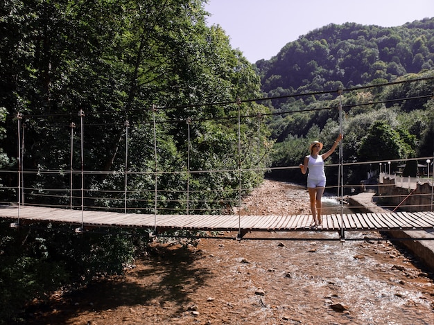 Das Mädchen geht in die Brücke und genießt den Tourismus durch den Wald.