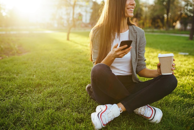 Das Mädchen hält das Telefon und den Kaffee in der Hand Sunset Summertime