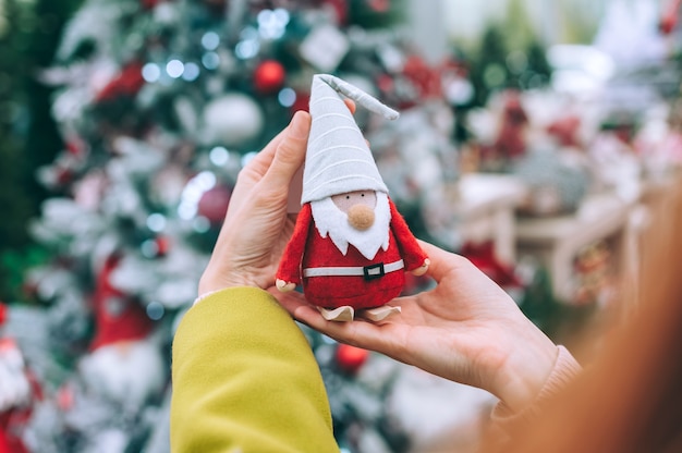 Das Mädchen hält den Weihnachtsmann - den Gnom in den Händen