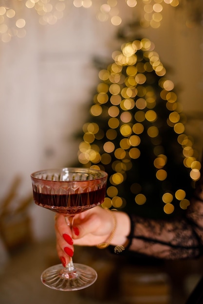 Das Mädchen hält ein Glas Sekt auf dem Hintergrund eines Weihnachtsbaums