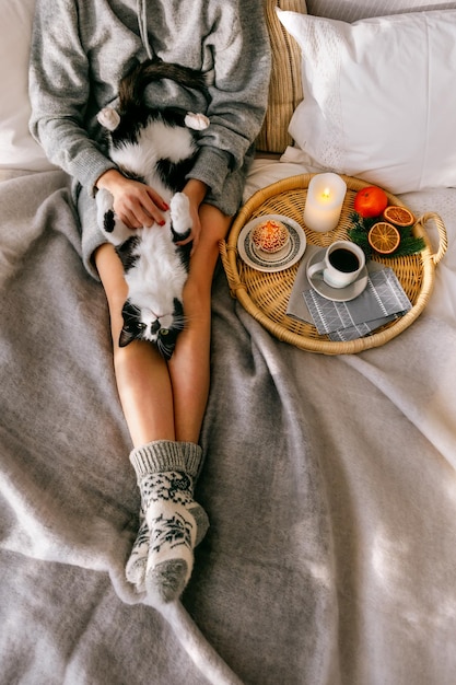 Das Mädchen hält eine Katze. Das Mädchen mit der Katze sitzt auf dem Bett. Frühstück im Bett