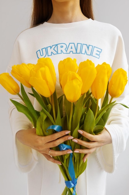 Das Mädchen hält einen riesigen Strauß Tulpen, Unterstützung für die Ukraine.