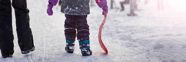 Das Mädchen hält einen roten Schlitten in ihren Händen, um die Rodelaktivitäten für Kinder und Te zu fahren