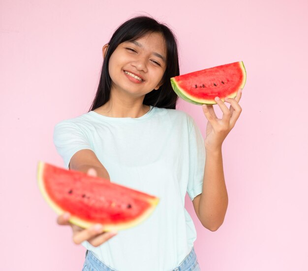 Das Mädchen hält rote Wassermelone auf rosa Hintergrund.