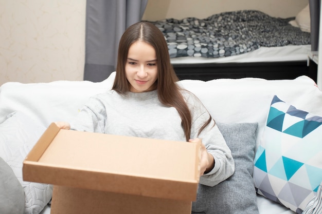 Das Mädchen hat einen Versandauftrag erhalten, packt die Kiste zu Hause aus