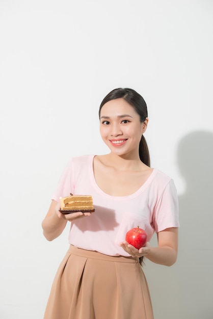 Das Mädchen hat in der einen Hand einen Apfel, in der anderen einen Kuchen.